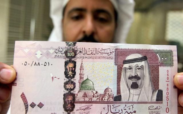 A Saudi banker displays the new one hund...Riyadh, SAUDI ARABIA: A Saudi banker displays the new one hundred riyal banknote bearing the portrait of Saudi King Abdullah bin Abdul Aziz al-Saud at a bank in Riyadh, 05 June 2007. The banknotes featuring the king are the fifth issue released by the Saudi Arabian Monetary Agency (SAMA). AFP PHOTO/HASSAN AMMAR (Photo credit should read HASSAN AMMAR/AFP/Getty Images)